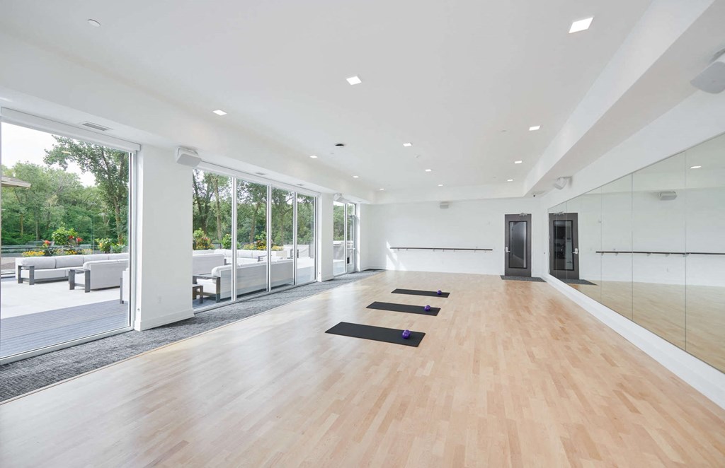 a large white room with yoga mats on the floor and large windows