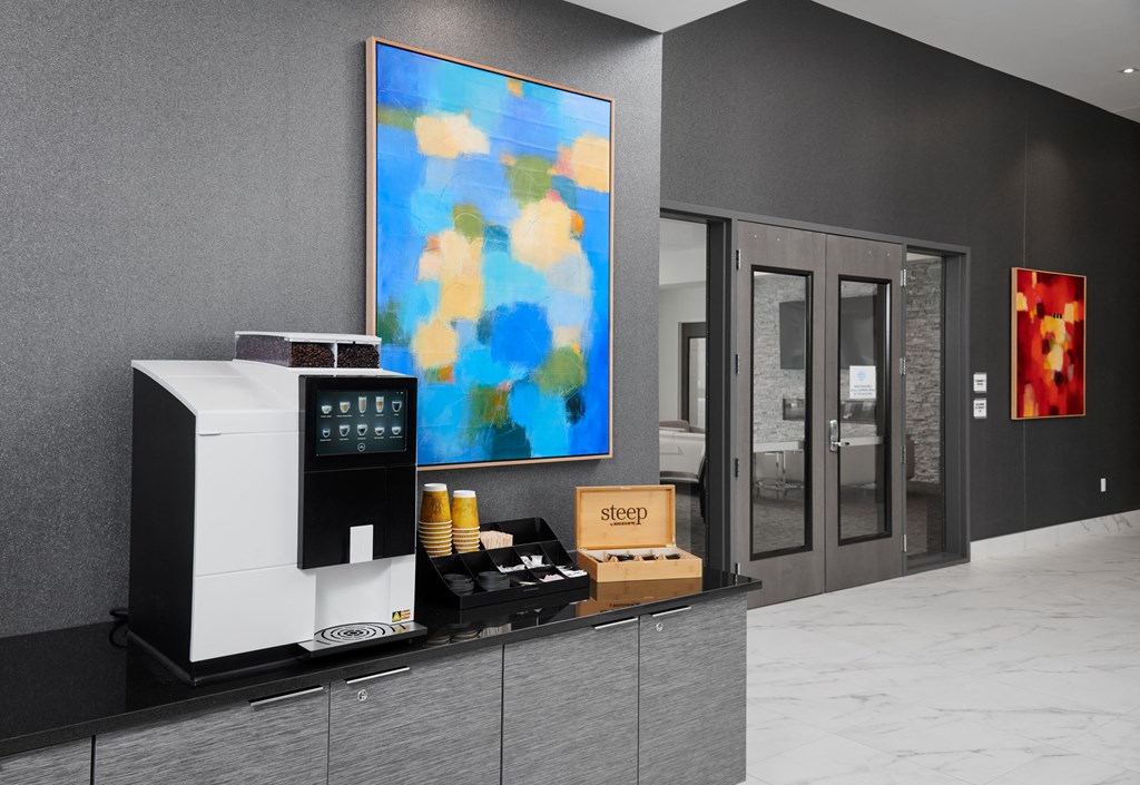 the lobby of a hotel with a coffee machine and a painting on the wall