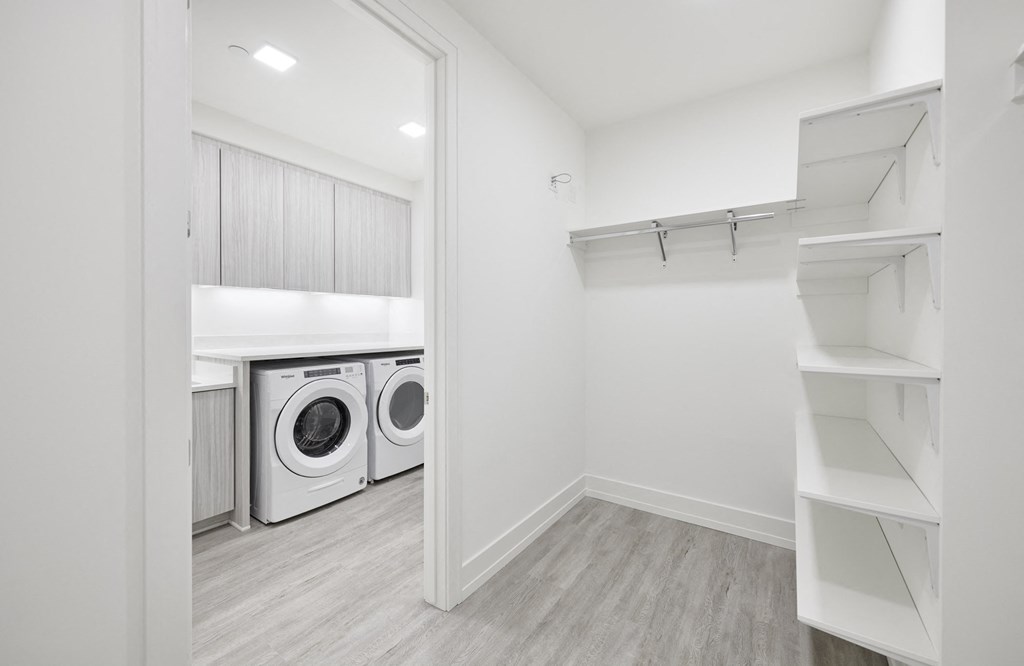 a washer and dryer in a laundry room with white walls and wood floors