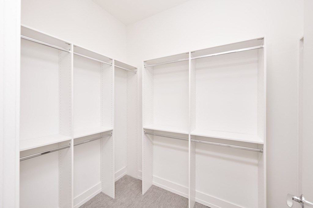 a walk in closet with white walls and white closet doors