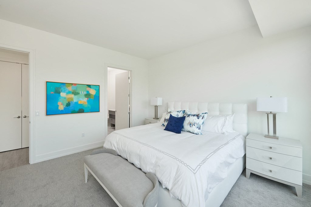 a white bedroom with a large bed and a blue painting on the wall