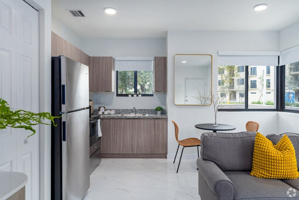 a kitchen and living room with a refrigerator and a sink