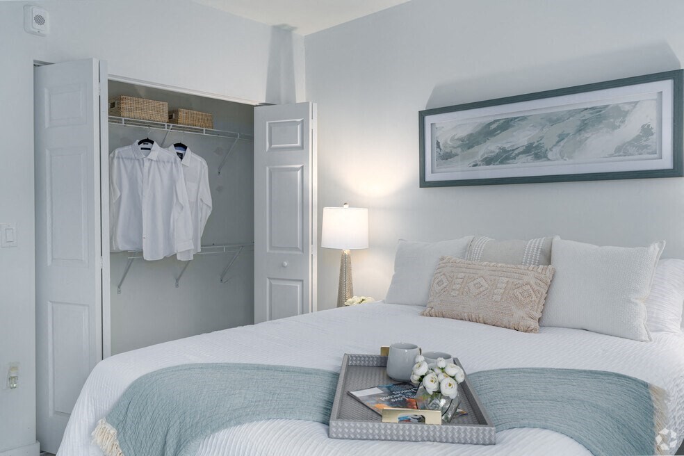 a bedroom with a bed and a closet with clothes hanging on it