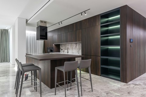 A modern kitchen with a bar area and grey chairs.