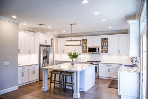 A kitchen with white cabinets and a large island.