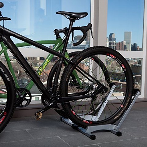 A black and green bike is leaning against a stand in front of a window.