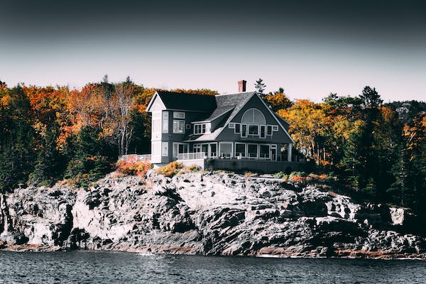 A house is built on a rocky outcrop by the water.