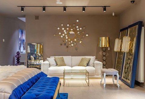 A living room with a white couch and a blue tufted bench.