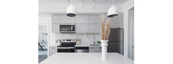 A modern kitchen with a white countertop and black appliances.