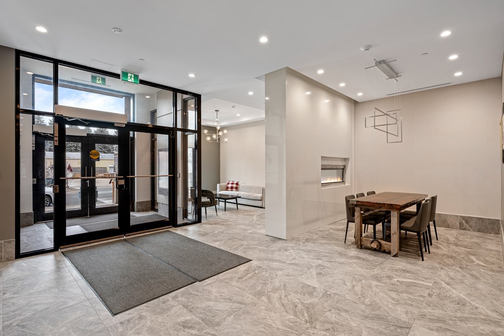 A modern interior with a black door, a grey rug, and a wooden table.