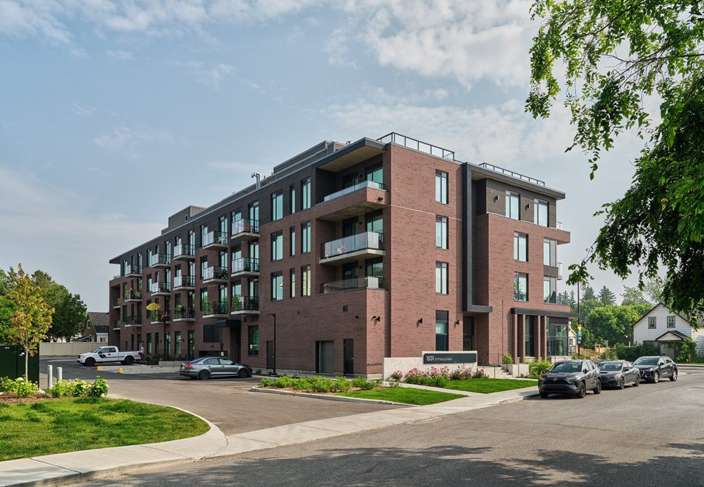 A modern brick building with a parking lot in front.