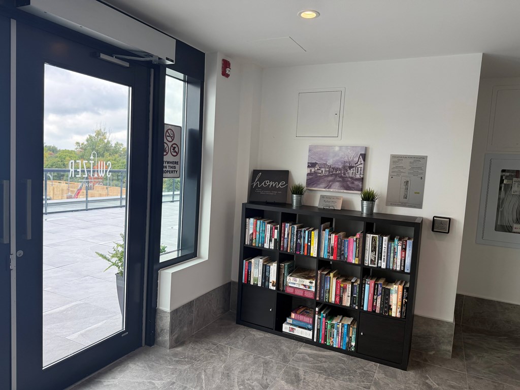 A black bookshelf filled with books in a room with a door and a window.