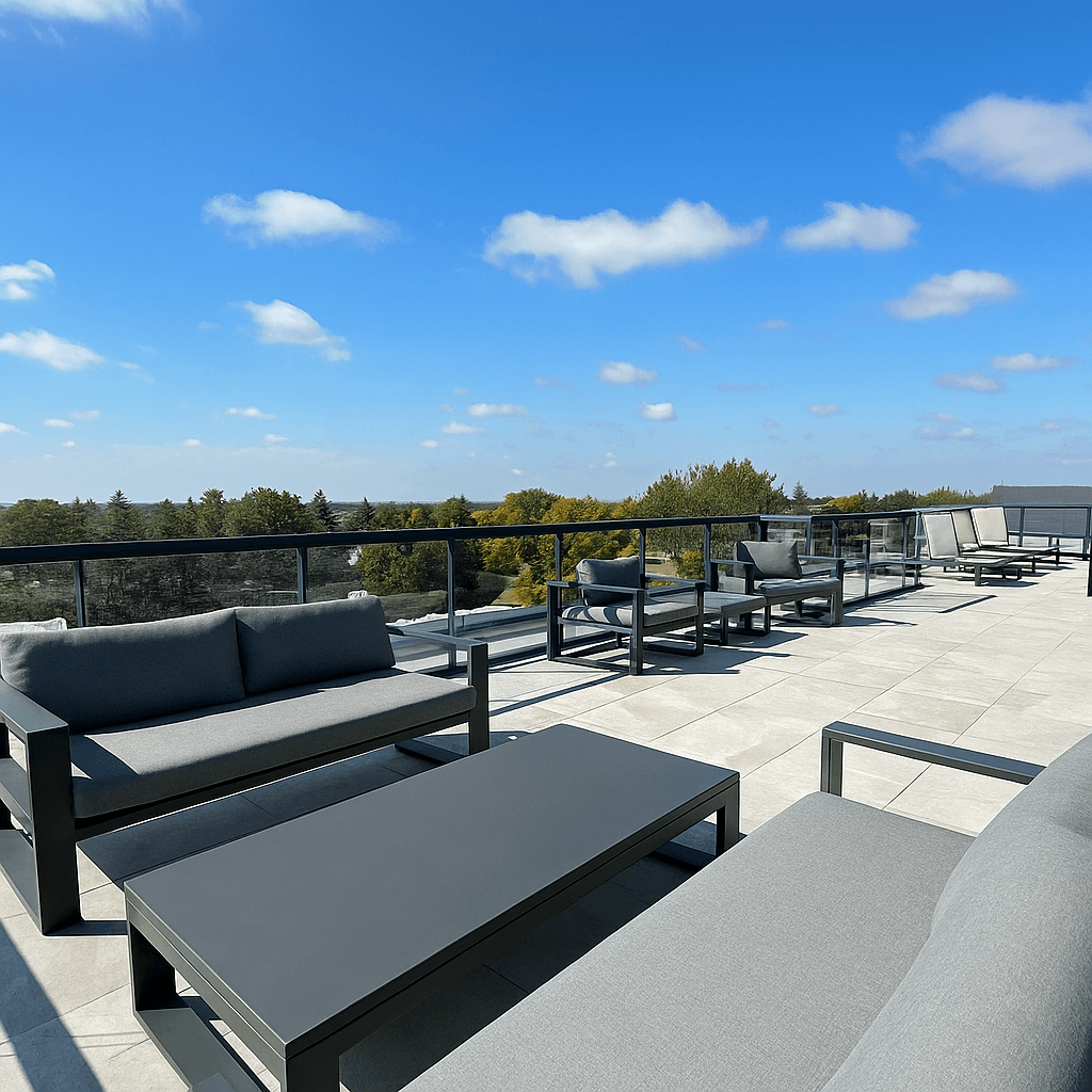 A patio with grey furniture and a blue sky with clouds.