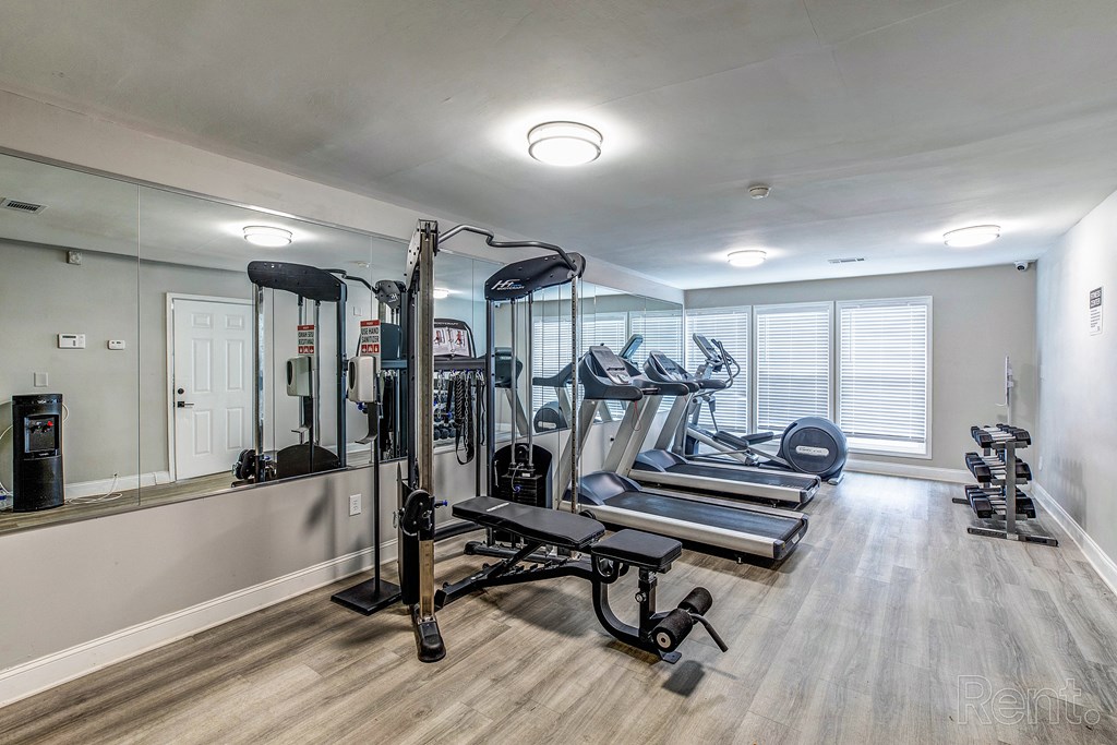 a gym with treadmills and other exercise equipment in a room with a mirror