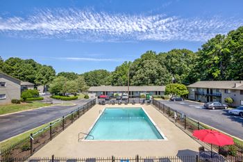 a swimming pool with an umbrella next to a parking lot