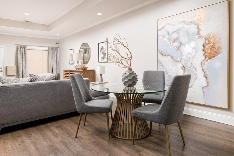 A modern dining room with a glass table and grey chairs.