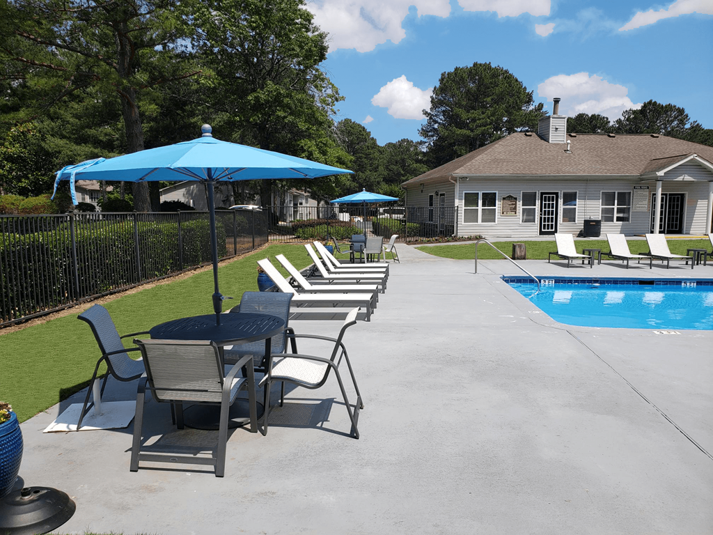 a swimming pool and patio with chairs and umbrellas