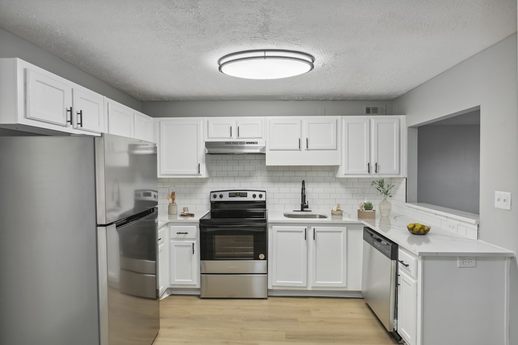 A modern kitchen with white cabinets and stainless steel appliances.