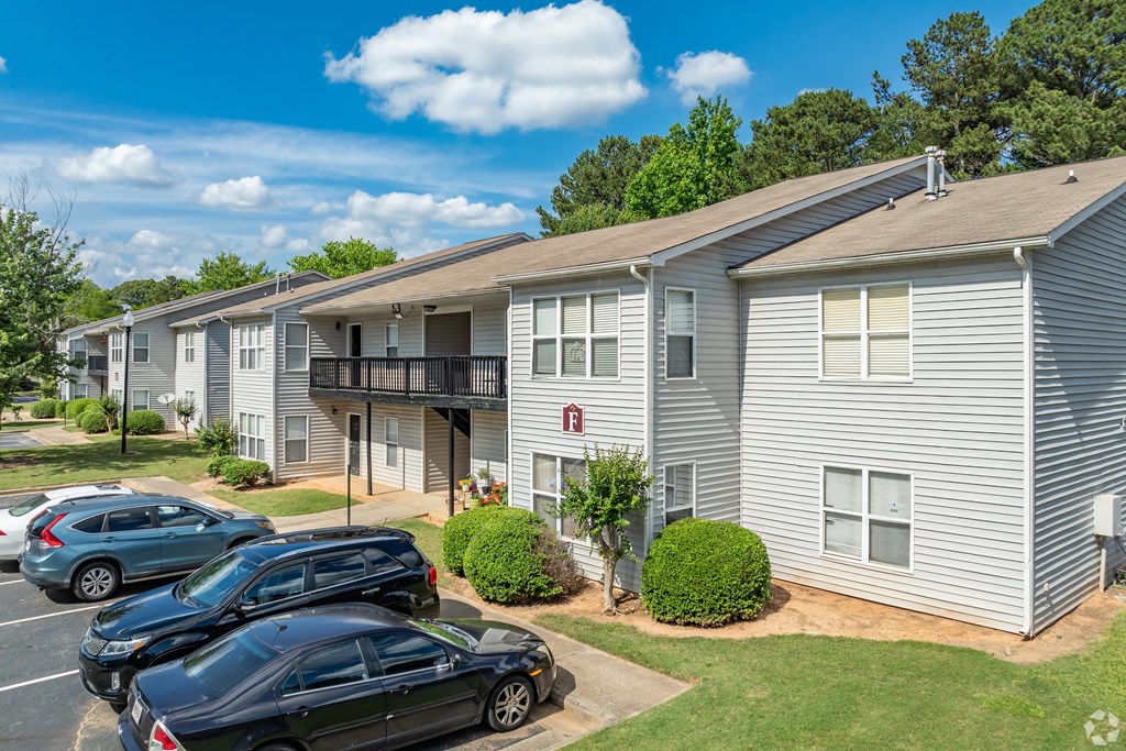 a row of apartment buildings with cars parked in a parking lot
