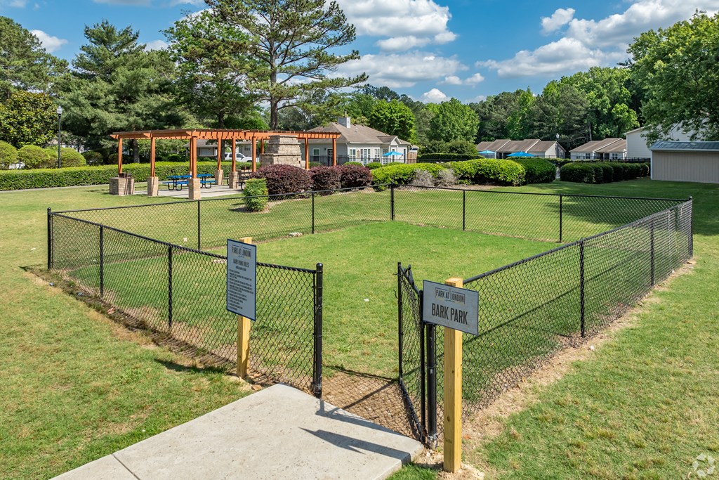 a fenced in park with a playground and a picnic area