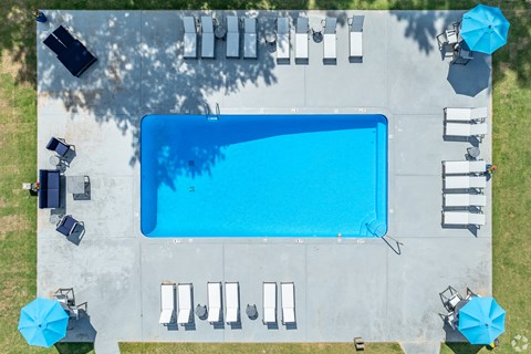 an aerial view of a pool with umbrellas and tables and chairs around it