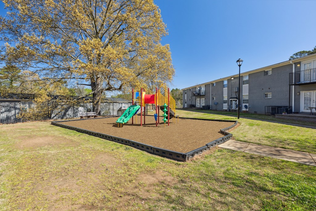 A playground with a slide and swings in a grassy area.