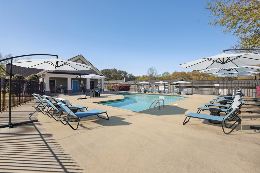 A pool area with sun loungers and a building in the background.