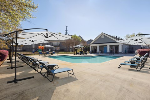 A pool area with sun loungers and a building in the background.