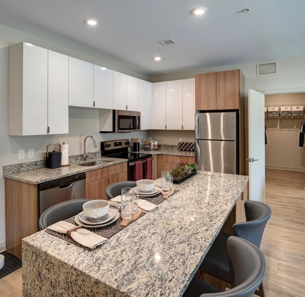 Apartments In Downtown Kalamazoo For Rent - 400 Rose - Kitchen With Granite Kitchen Island, Wood-Style Flooring, Sleek White Cabinets, And Stainless-Steel Appliances