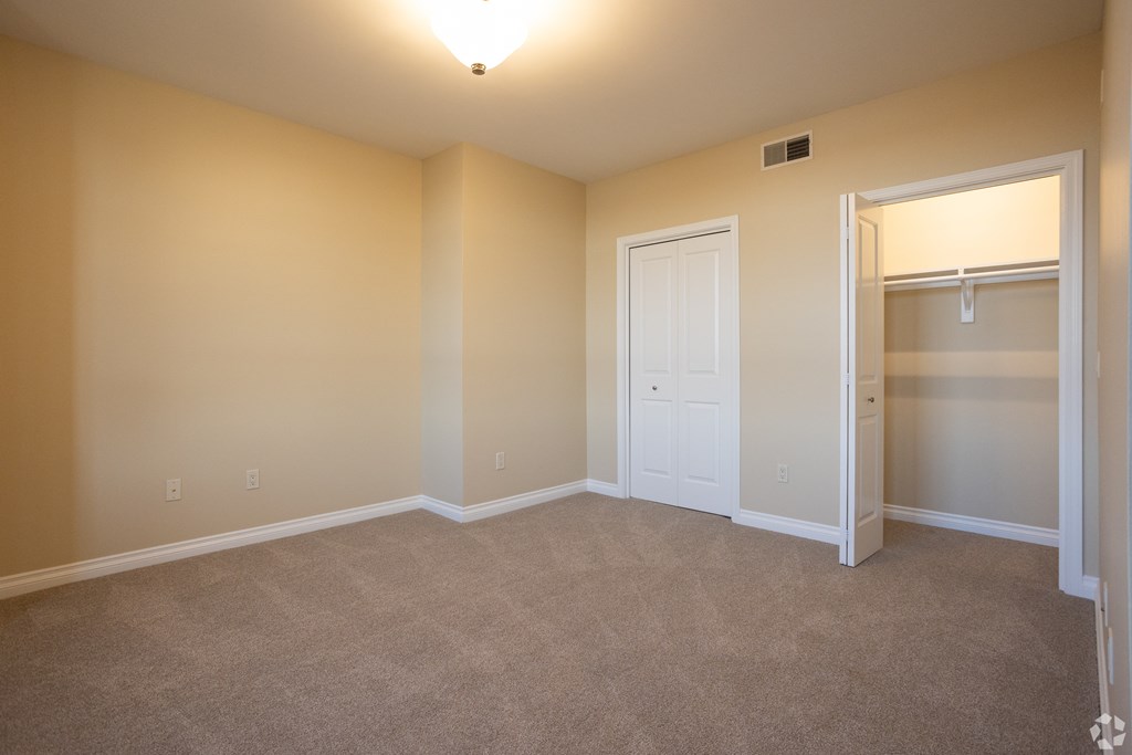 an empty living room with a closet and a door to a wardrobe