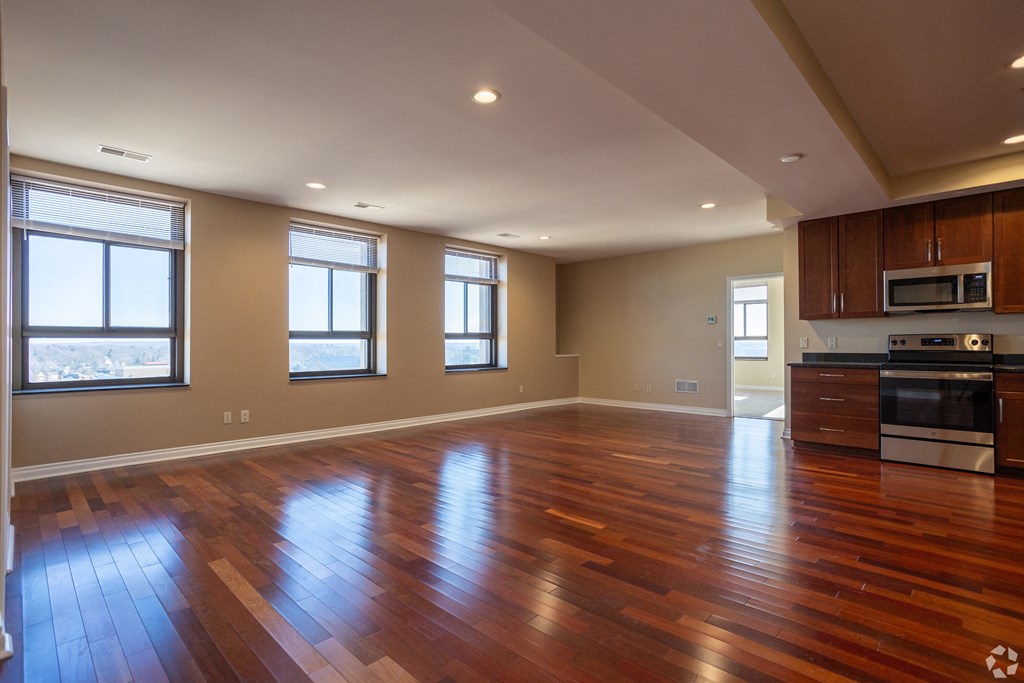 an empty living room with wood floors and a kitchen