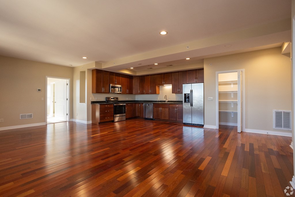 an empty living room and kitchen with wood flooring