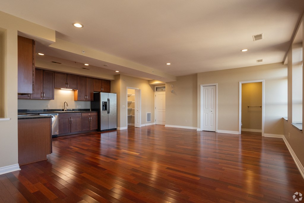 an empty living room and kitchen with wood floors
