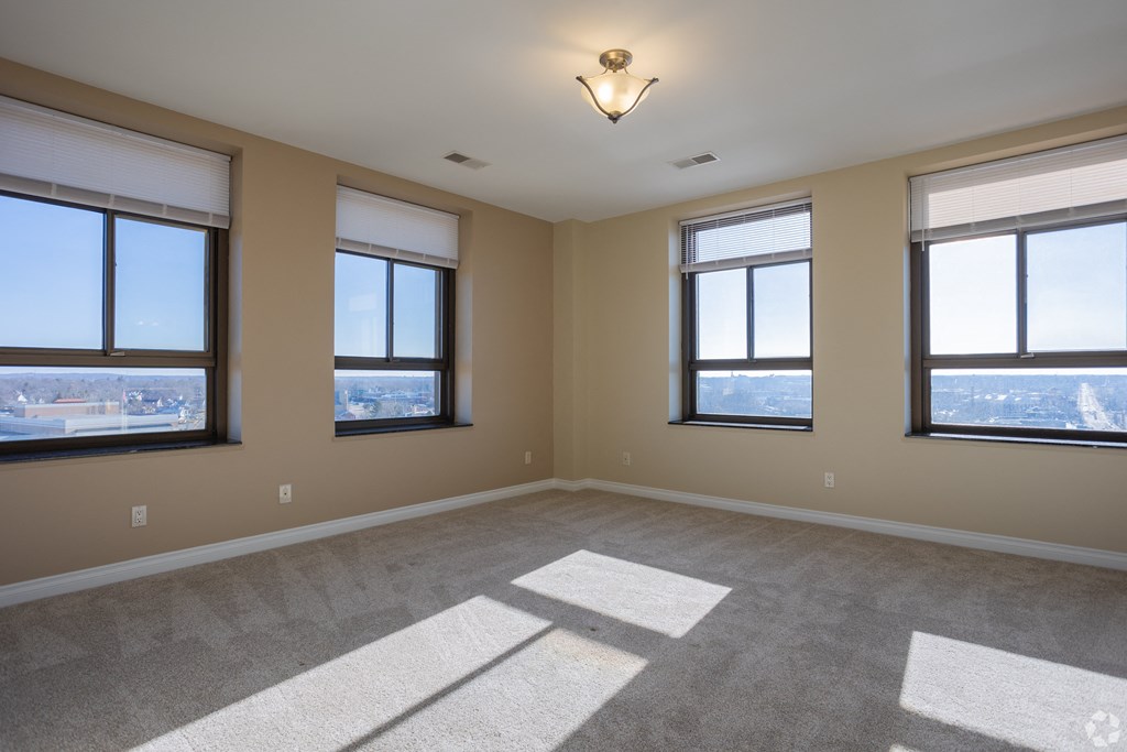 an empty living room with three windows and a ceiling light