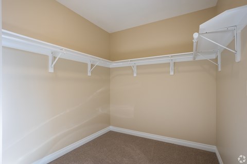 a spacious closet in a home with white racks on the wall
