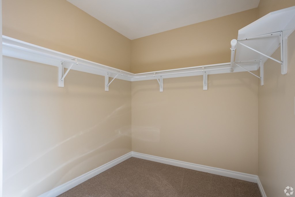 a spacious closet in a home with white racks on the wall