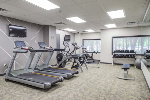 a gym with treadmills and other exercise equipment and a television