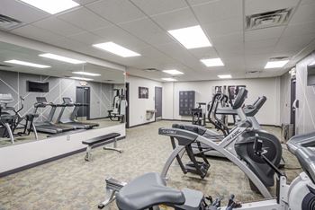 a gym with cardio equipment and weights in a building with white walls