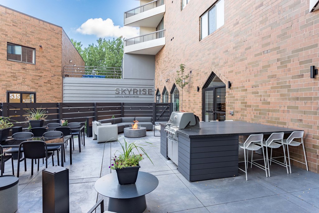 a patio with tables and chairs and a bar and a brick building