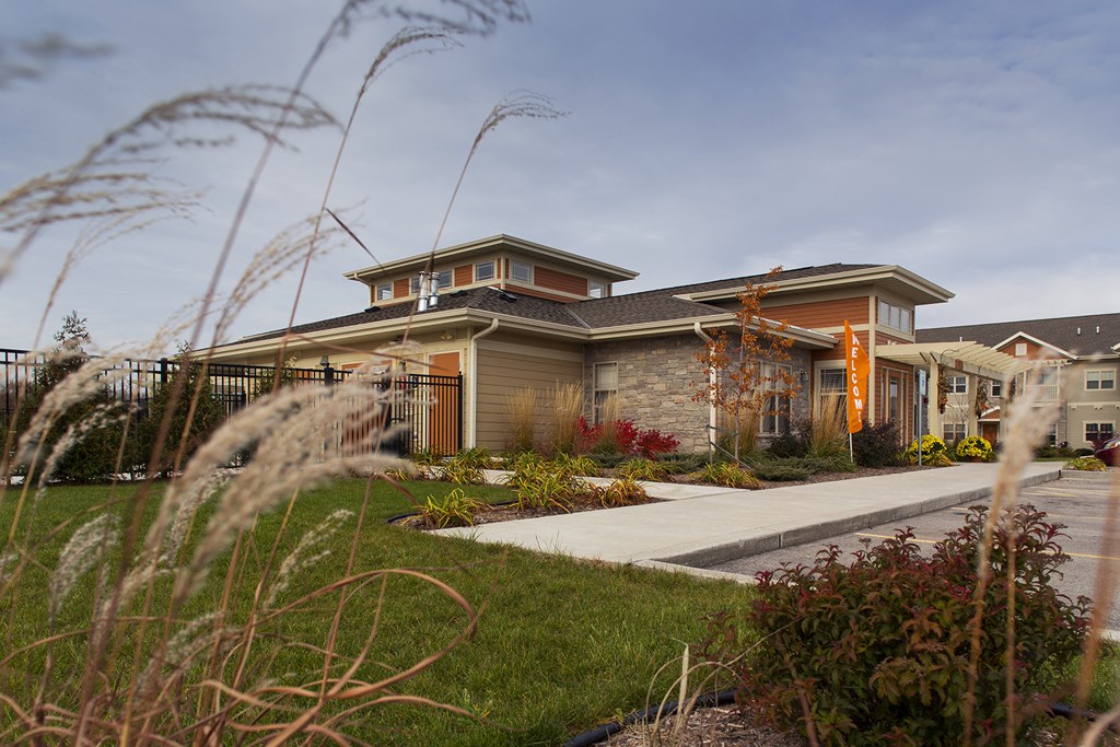 a home with a sidewalk in front of it and tall grass
