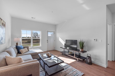 A living room with a brown couch, a black coffee table, and a flat screen TV.