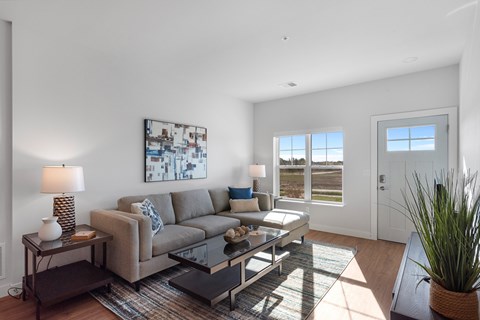 A living room with a grey couch and a painting on the wall.