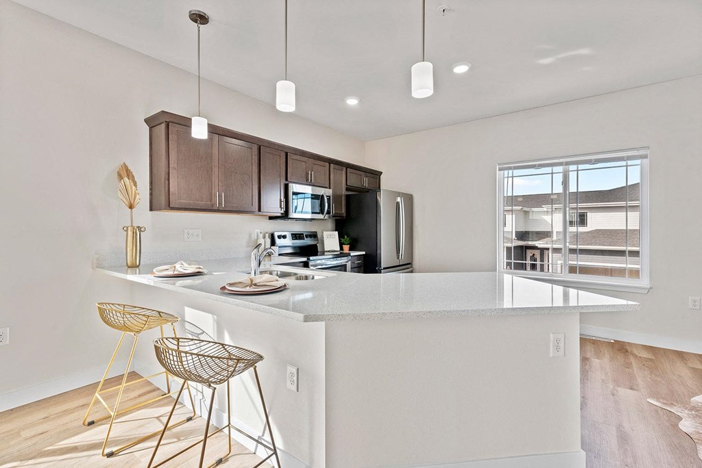 an open kitchen with a large island with bar stools at The Residences Apartments at Bear Tree, DeForest, WI 53532