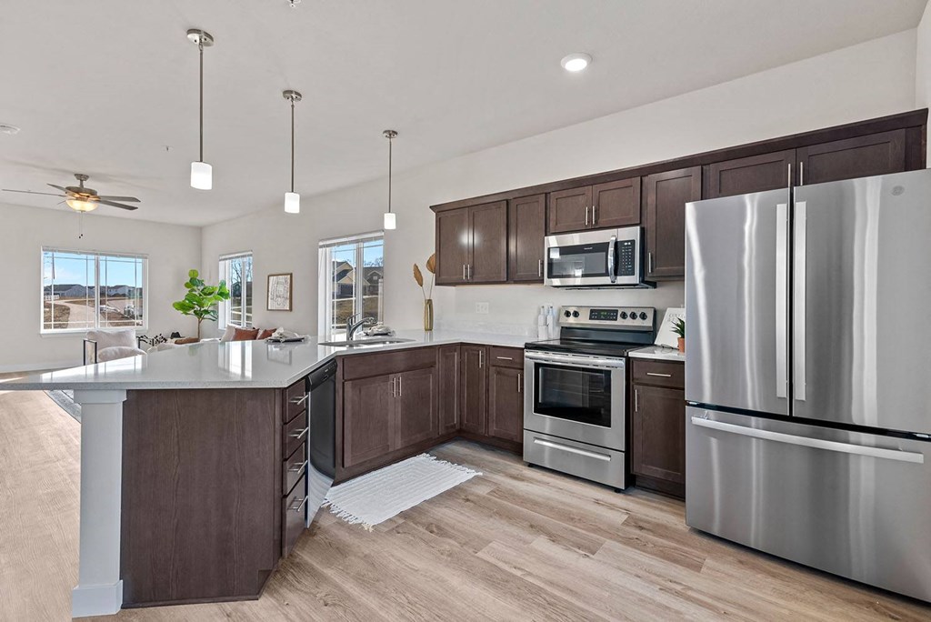a kitchen with stainless steel appliances and wooden cabinets at The Residences Apartments at Bear Tree, DeForest, 53532