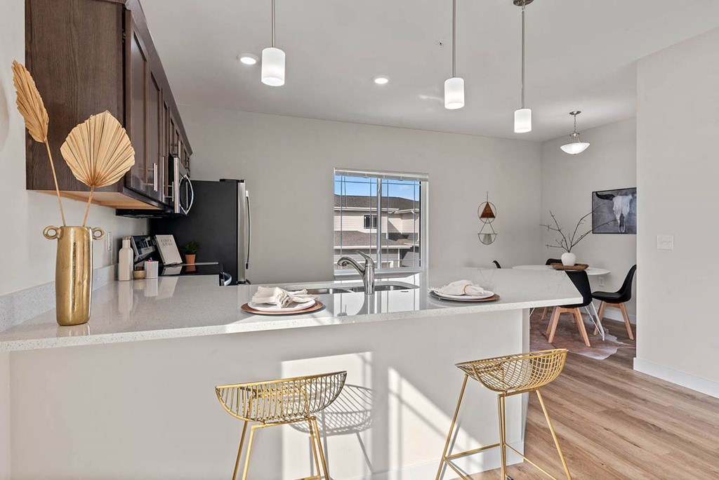 an open kitchen and dining area with a table and chairs at The Residences Apartments at Bear Tree, WI, DeForest