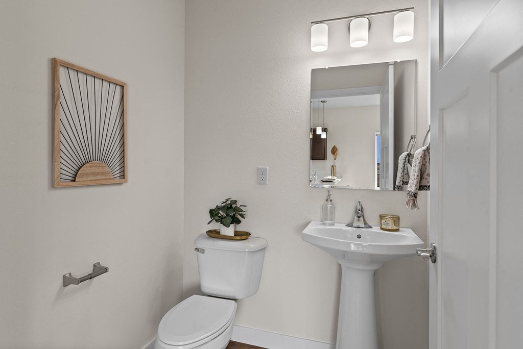 a bathroom with a toilet sink and a mirror at The Residences Apartments at Bear Tree, DeForest, Wisconsin