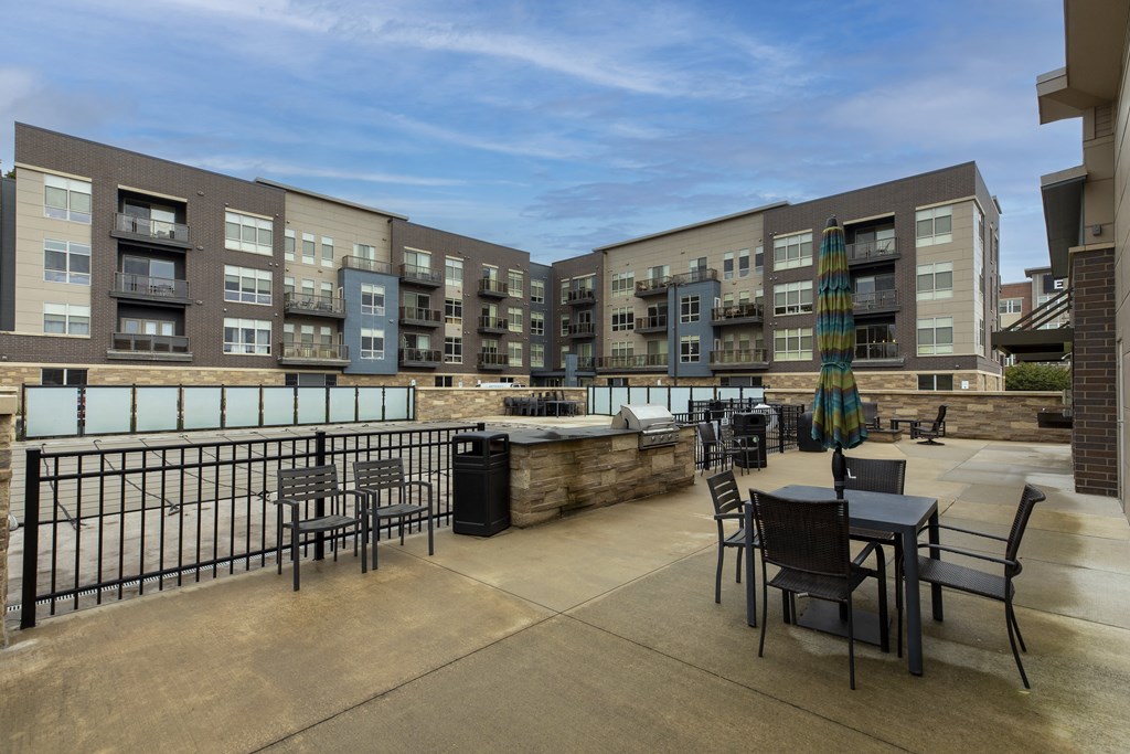 a patio with tables and chairs and an apartment building