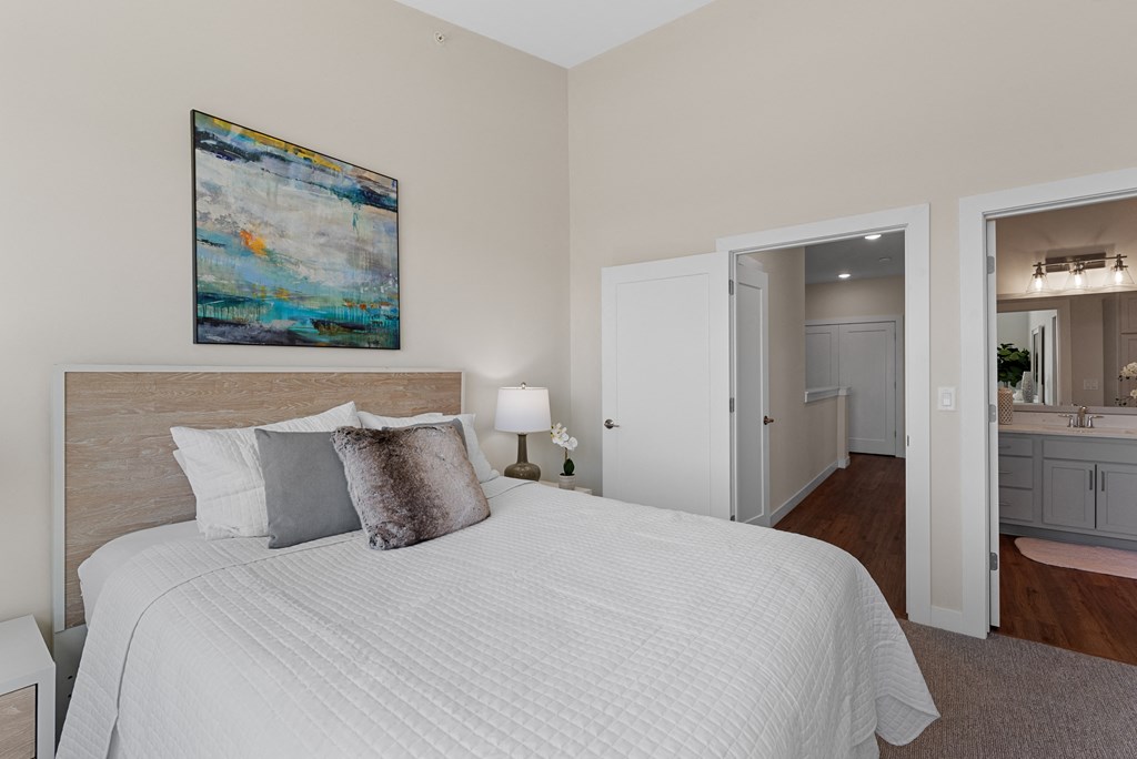 a bedroom with a large bed and a painting on the wall at Tivoli Green Apartments & Townhomes, Mount Pleasant, WI