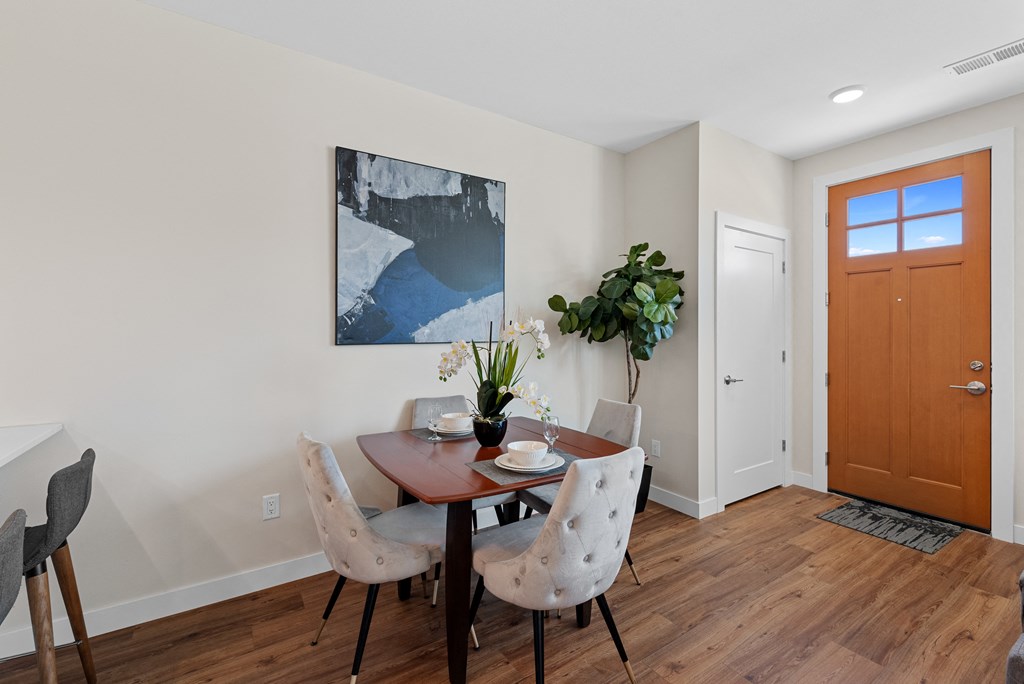 a dining room with a table and chairs and a wooden door at Tivoli Green Apartments & Townhomes, Mount Pleasant, WI
