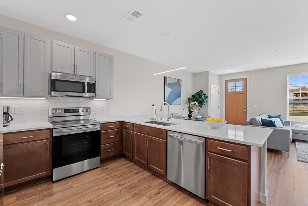 a large kitchen with white counter tops and stainless steel appliances